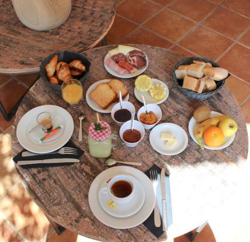 un tavolo ricoperto di piatti di prodotti per la colazione e bevande di Hôtel Casa Rossa & Spa a LʼÎle-Rousse