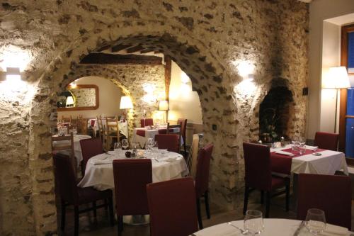 comedor con mesas y pared de piedra en Logis Hôtel & Restaurant - Le Manoir de Sauvegrain, en Saint-Lambert