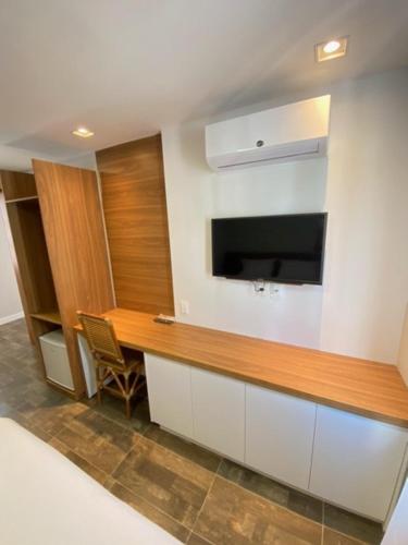 a kitchen with a desk and a television on a wall at Swell Praia Hotel in Natal