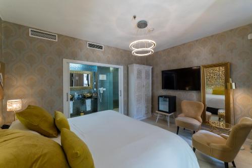 een slaapkamer met een groot wit bed en een televisie bij El Rey Moro Hotel Boutique in Sevilla