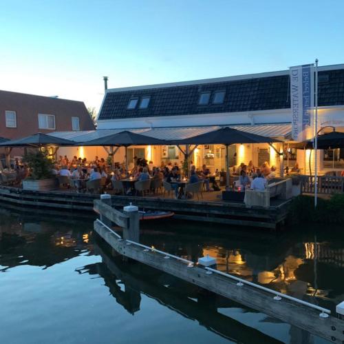 un grupo de personas sentadas en un restaurante junto al agua en De Watersport Heeg, en Heeg