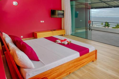 a bedroom with a bed with a red wall at Hôtel Villa Les Orchidées in Ambatoloaka