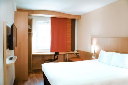 Habitación de hotel con cama y ventana en Ibis Győr, en Győr