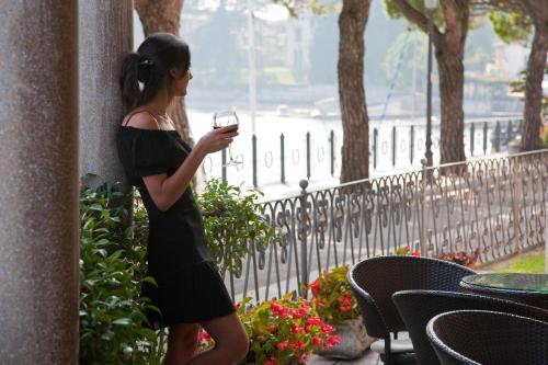 Eine Frau in einem schwarzen Kleid, die ein Handy hält. in der Unterkunft Hotel Lenno in Lenno