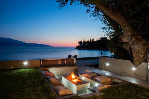 a fire pit under a tree next to the water at Spa Villa Skaloma in Nafpaktos