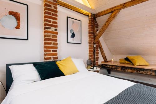 - une chambre avec un lit blanc et un mur en briques dans l'établissement Principia Apartments, à Turda