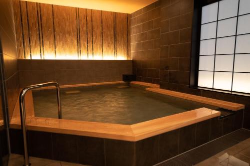 une salle de bains carrelée de brun avec bain à remous dans l'établissement Almont Hotel Nippori, à Tokyo