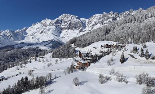 uma montanha coberta de neve com uma casa no meio em Das Grünholz Aparthotel em Mühlbach am Hochkönig