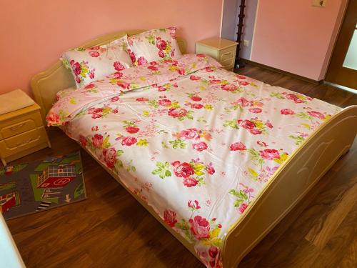 un letto con fiori rosa in una camera da letto di Вілла на Роші. Власна територія, мангал, альтанка. a Černivci