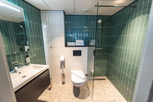 een groene betegelde badkamer met een toilet en een wastafel bij Boutique Hotel Zaan in Zaandijk