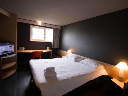 une chambre d'hôtel avec un lit et une télévision dans l'établissement ibis Rennes Beaulieu, à Cesson-Sévigné