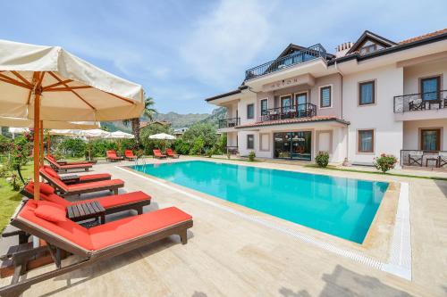 eine Villa mit einem Pool mit Stühlen und einem Sonnenschirm in der Unterkunft Gocek Arion Hotel in Göcek