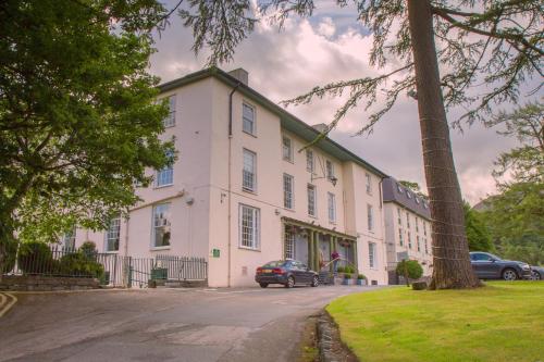 un grand bâtiment blanc avec des voitures garées devant lui dans l'établissement Royal Victoria Hotel Snowdonia, à Llanberis