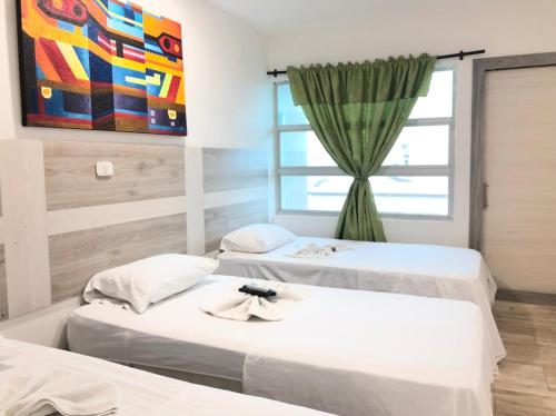 twee bedden in een kamer met een raam bij Hotel ibiza Central in Montería