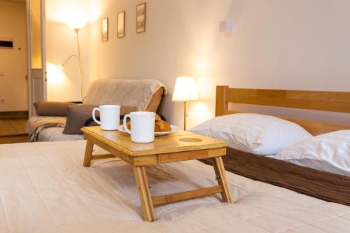 Cette chambre comprend un lit et une table avec deux tasses. dans l'établissement Peaceful studio on Rynok Square, à Lviv