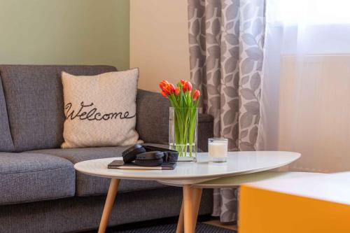 ein Wohnzimmer mit einem Sofa und einem Tisch mit Blumen in der Unterkunft Landhotel Gutshof in Hartenstein