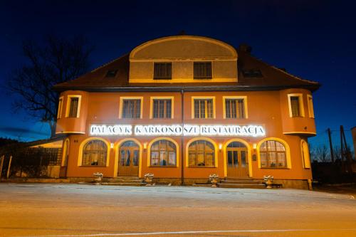 un grande edificio giallo con un cartello sopra di Pałacyk Karkonosze koło Karpacza a Karpacz