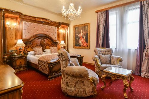 um quarto com uma cama e cadeiras e um lustre em Premier Prezident Garni Hotel and Spa em Sremski Karlovci