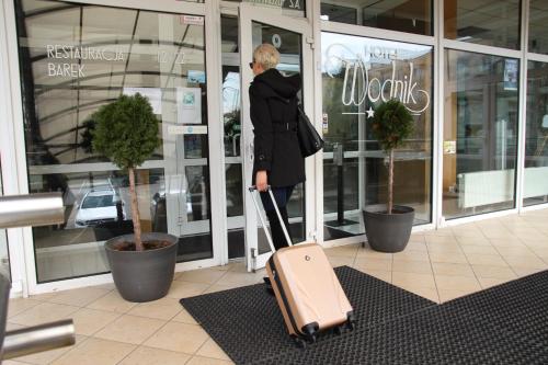 una mujer tirando una maleta delante de una tienda en Hotel Wodnik, en Giżycko