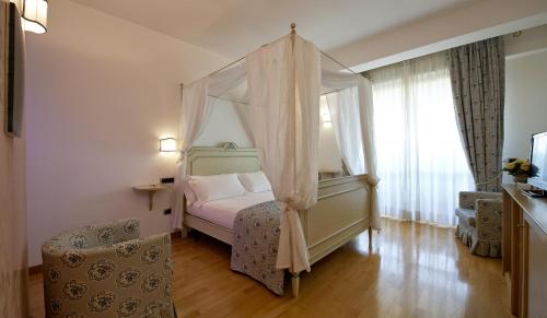 una camera con letto a baldacchino e finestra di Hotel Villa Poseidon & Events a Salerno