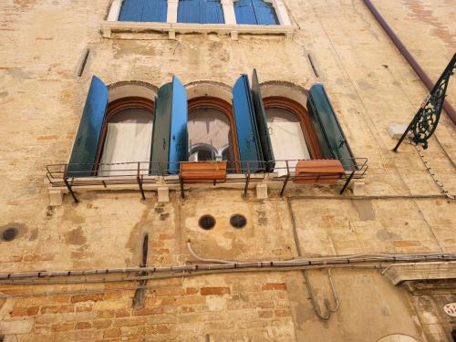 un edificio con tres ventanas con tablas de surf azules. en Suite Doge Marcello, en Venecia