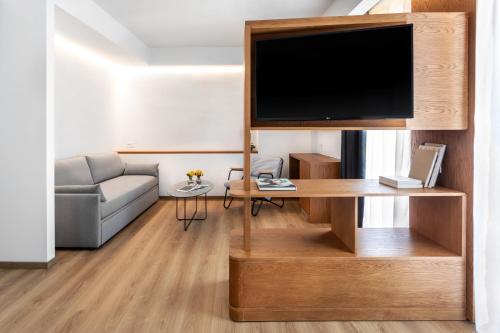 een woonkamer met een flatscreen-tv op een houten entertainmentcentrum bij DAYS City Suites in Patra