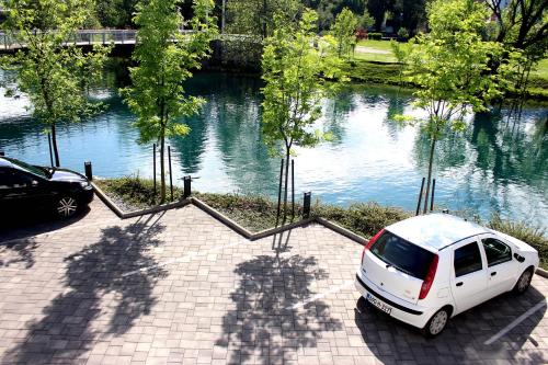 un coche blanco aparcado en un aparcamiento junto a un río en Holiday In Bihać, en Bihać