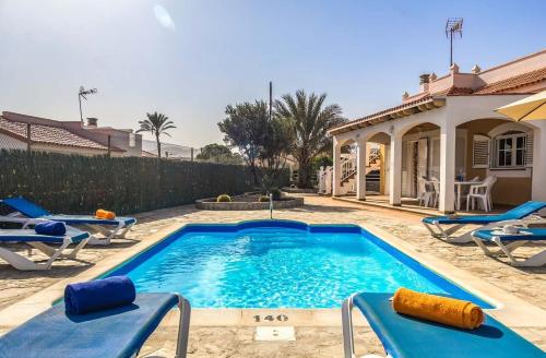 a swimming pool with chairs and a house at Vv Tirma in Caleta De Fuste