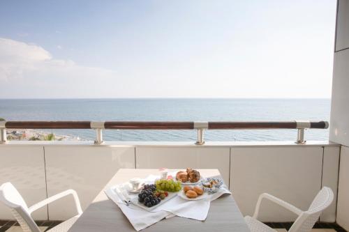 uma mesa com um prato de comida numa varanda com o oceano em Grand Hotel Salerno em Salerno