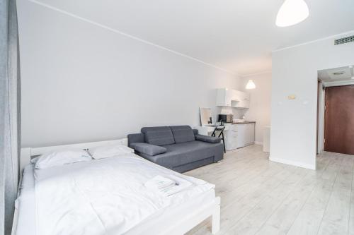 Habitación blanca con cama y sofá en Apartamenty Proeko Polonia, en Kołobrzeg