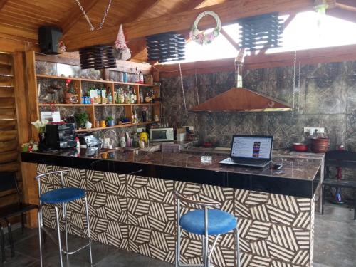 a bar with blue stools and a laptop on a counter at Садиба Герасімових in Kamianets-Podilskyi