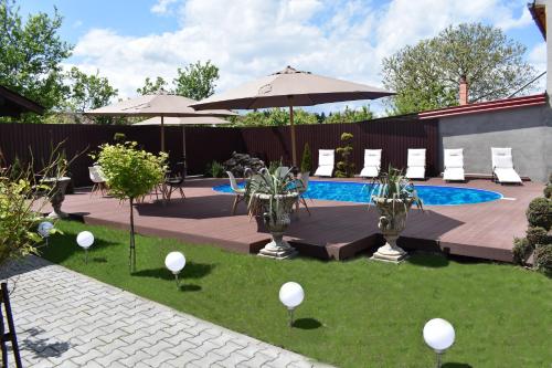 une cour avec une piscine, des chaises et des parasols dans l'établissement Pensiunea Casa Zece, à Turda