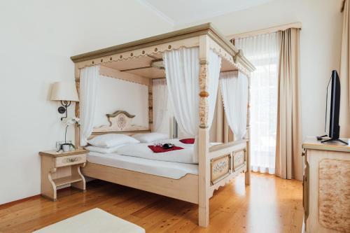 ein Schlafzimmer mit einem Himmelbett und einem TV in der Unterkunft Hotel de France Wiesbaden City in Wiesbaden