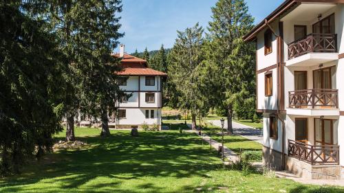 een appartementencomplex met een tuin met bomen bij “Family аpart - Смолянски езера“ in Smolyan