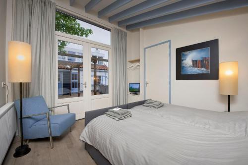 ein Schlafzimmer mit einem Bett und einem blauen Stuhl in der Unterkunft B&B Zee van Tijd Domburg in Domburg