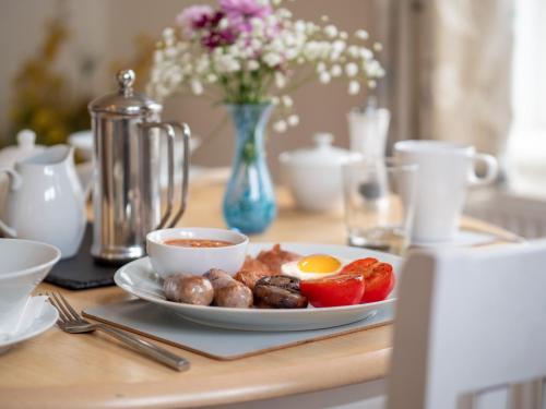 une assiette de denrées alimentaires sur une table avec des œufs et des tomates dans l'établissement Avalon House B&B, à Lyndhurst