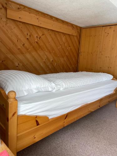 1 cama en una cabaña de madera con sábanas blancas en Hotel Bernina Hospiz, en Berninahäuser