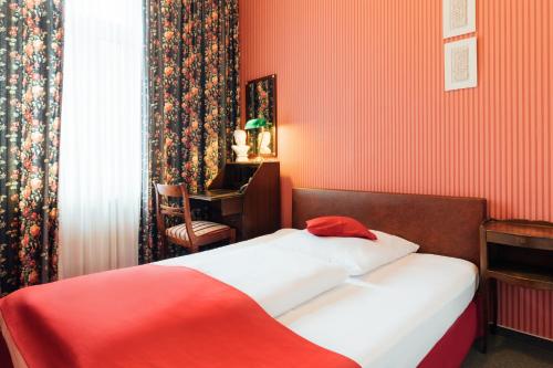 - une chambre rouge avec un lit et un bureau dans l'établissement Das Kleine Hotel in ruhiger Stadtlage, à Wiesbaden