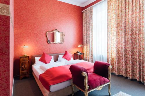 - une chambre rouge avec un lit et une chaise dans l'établissement Das Kleine Hotel in ruhiger Stadtlage, à Wiesbaden