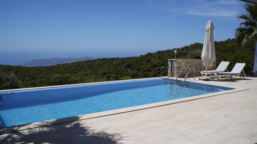 einen Pool mit 2 Stühlen und einem Sonnenschirm in der Unterkunft Villa Emilie Kas in Kaş