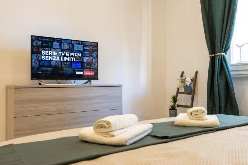 um quarto com televisão e toalhas numa cama em Green Pearl ✰✰✰✰✰ Appartamento a 100 metri dal lago em Arona