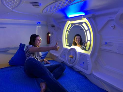 Space Night Capsule Hostel في برلين: بنتان جالستان على سرير في غرفة مع مرآة