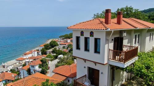 um edifício branco com um telhado vermelho e o oceano em Aegean Blue - Villas Stivachtis em Agios Ioannis Pelio