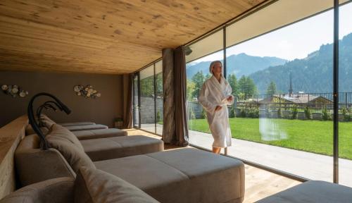 ヴィーゴ・ディ・ファッサにあるCiampedie Luxury Alpine Spa Hotelの大きなガラス窓のある部屋に立つ男