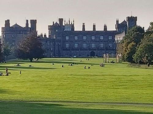 un gran castillo con gente en un campo delante de él en Castle Lodge Kilkenny, en Kilkenny