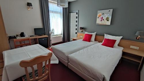 a hotel room with two beds with red pillows at La Chrysalide in Étalle