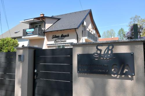 uma casa com um portão preto em frente a uma cerca em Silver Beach Apartments em Siófok