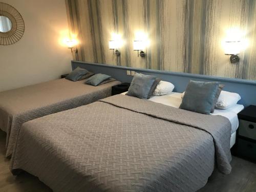 um quarto de hotel com duas camas e duas lâmpadas em Hôtel Saint Philibert em Tournus