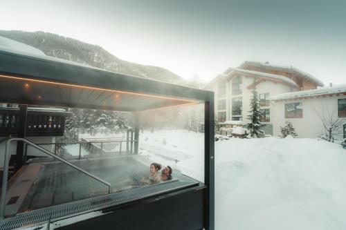 dos niños jugando en un jacuzzi en la nieve en Alpen Resort & Spa, en Zermatt