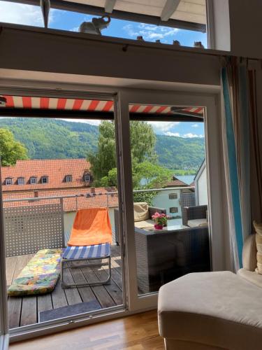 a room with a balcony with a bed and a sliding glass door at FeWo mit Seeblick in Bodensdorf